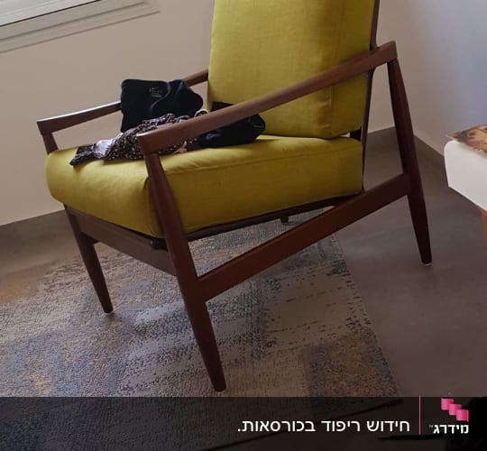כיסא מרופד בצבע צהוב עם בגדים עליו